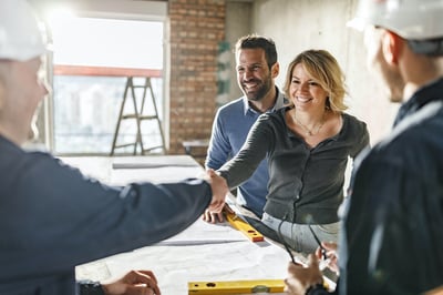 couple talking with construction leads - woman shaking mans hand